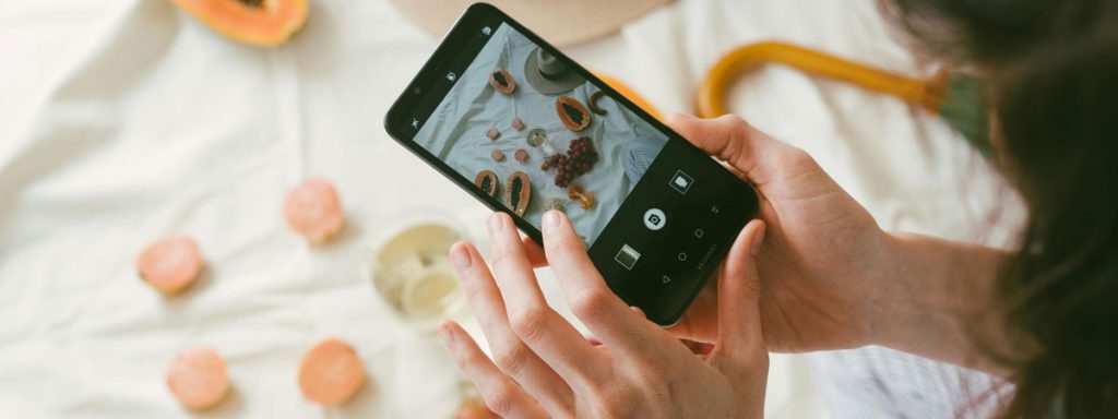 Eine Frau fotografiert Früchte mit einem Handy.